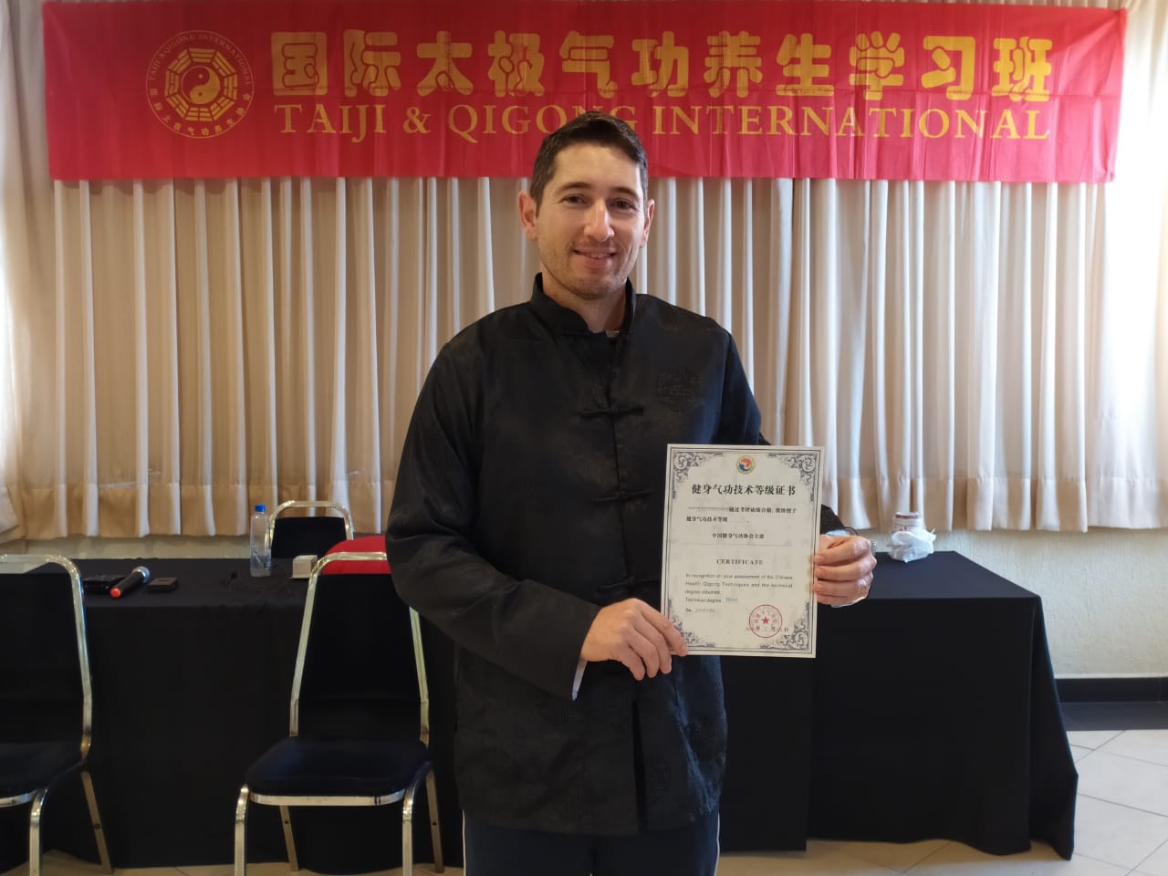 Marcos Martini exibindo um certificado durante uma formação internacional de Qi Gong