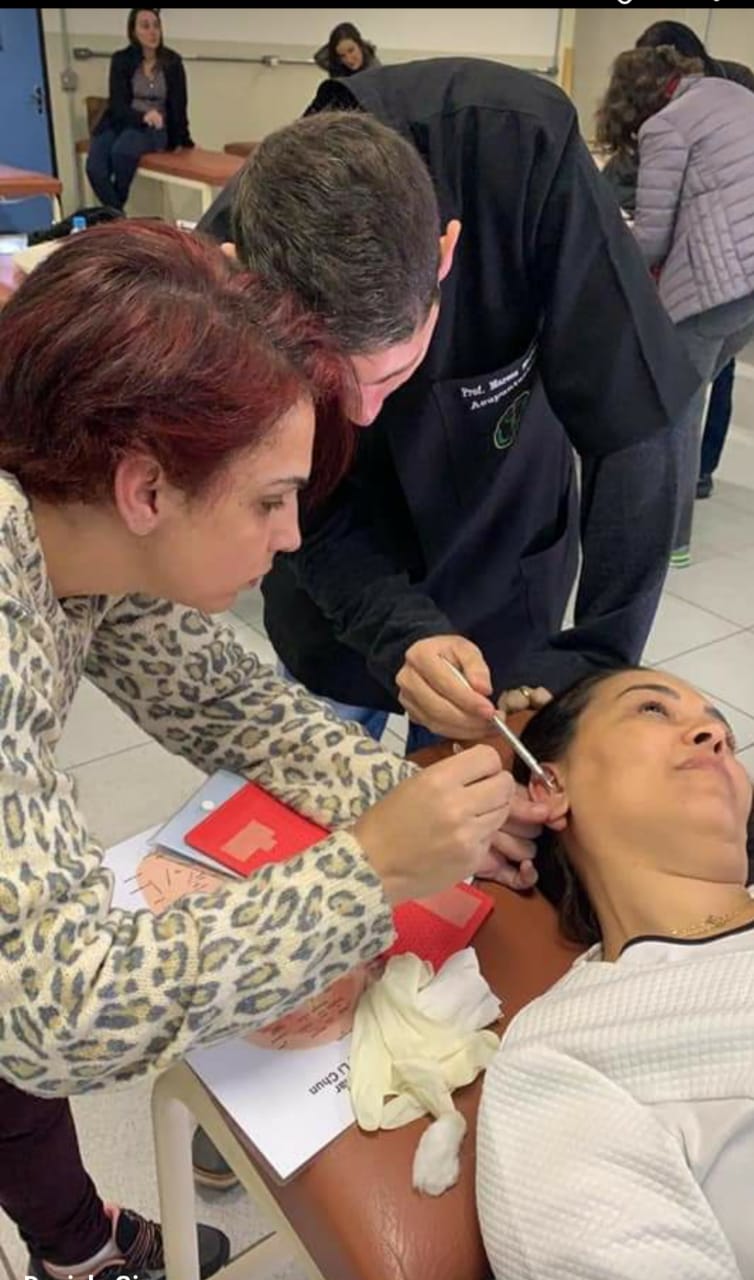 Aluna praticando Auriculoterapia com acompanhamento durante uma aula